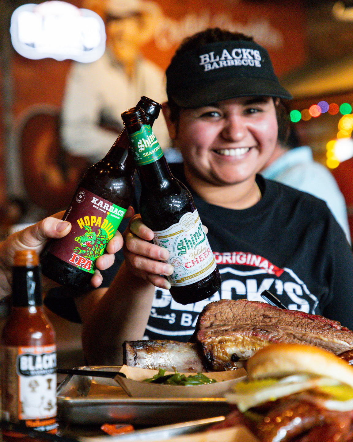 Black's BBQ Employee celebrating with a beer & brisket