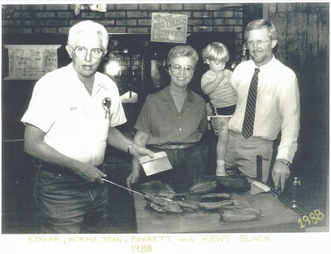 Edgar, Norma Jean, Barrett, and Kent Black slicing brisket in 1988.